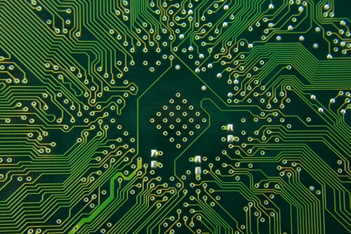 Nahaufnahme einer grünen Elektronikplatine mit feinen Schaltkreisen und Komponenten.